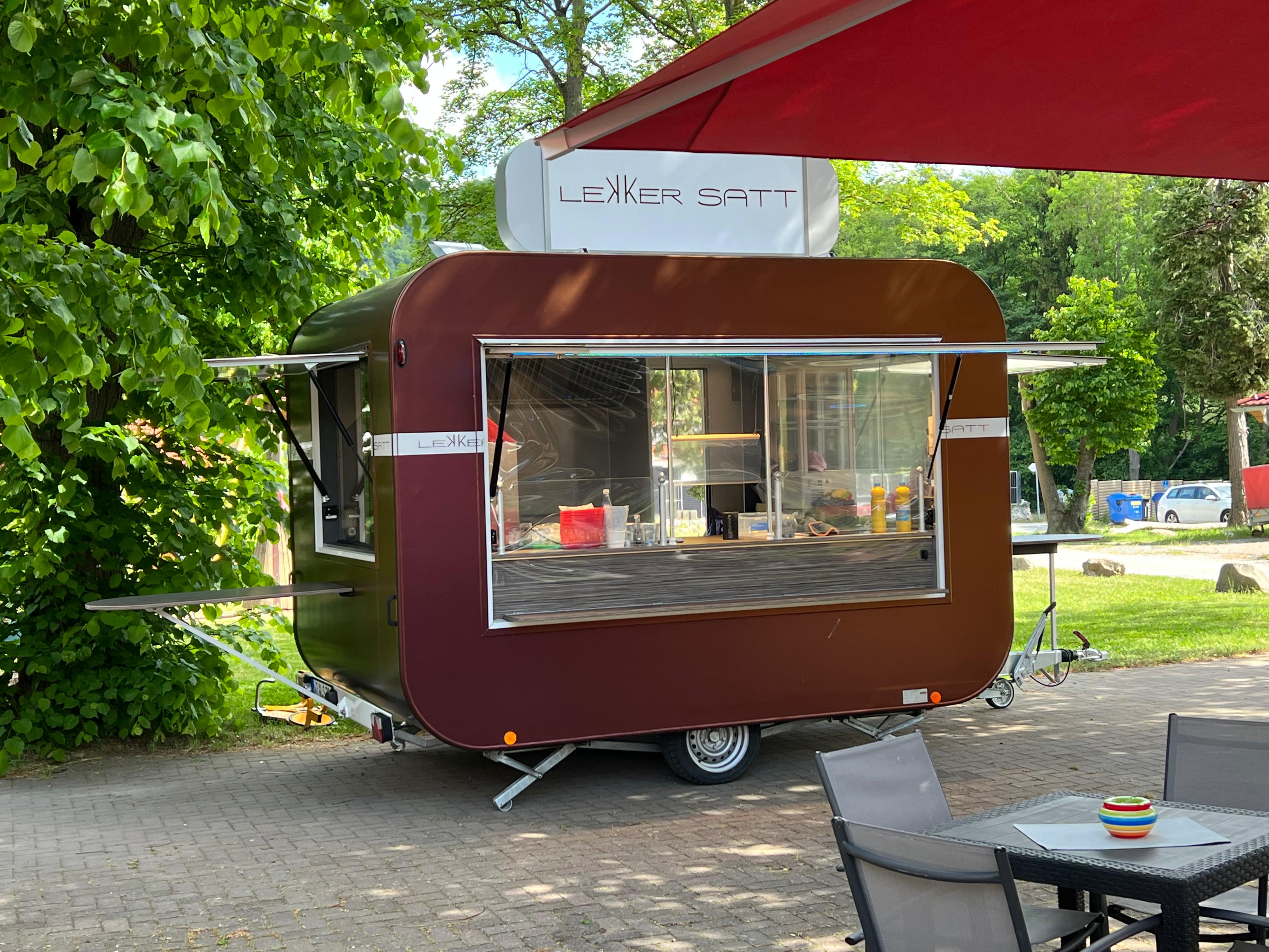 Lekker Satt Food Trailer im Grünen mit geöffneter Ausgabe