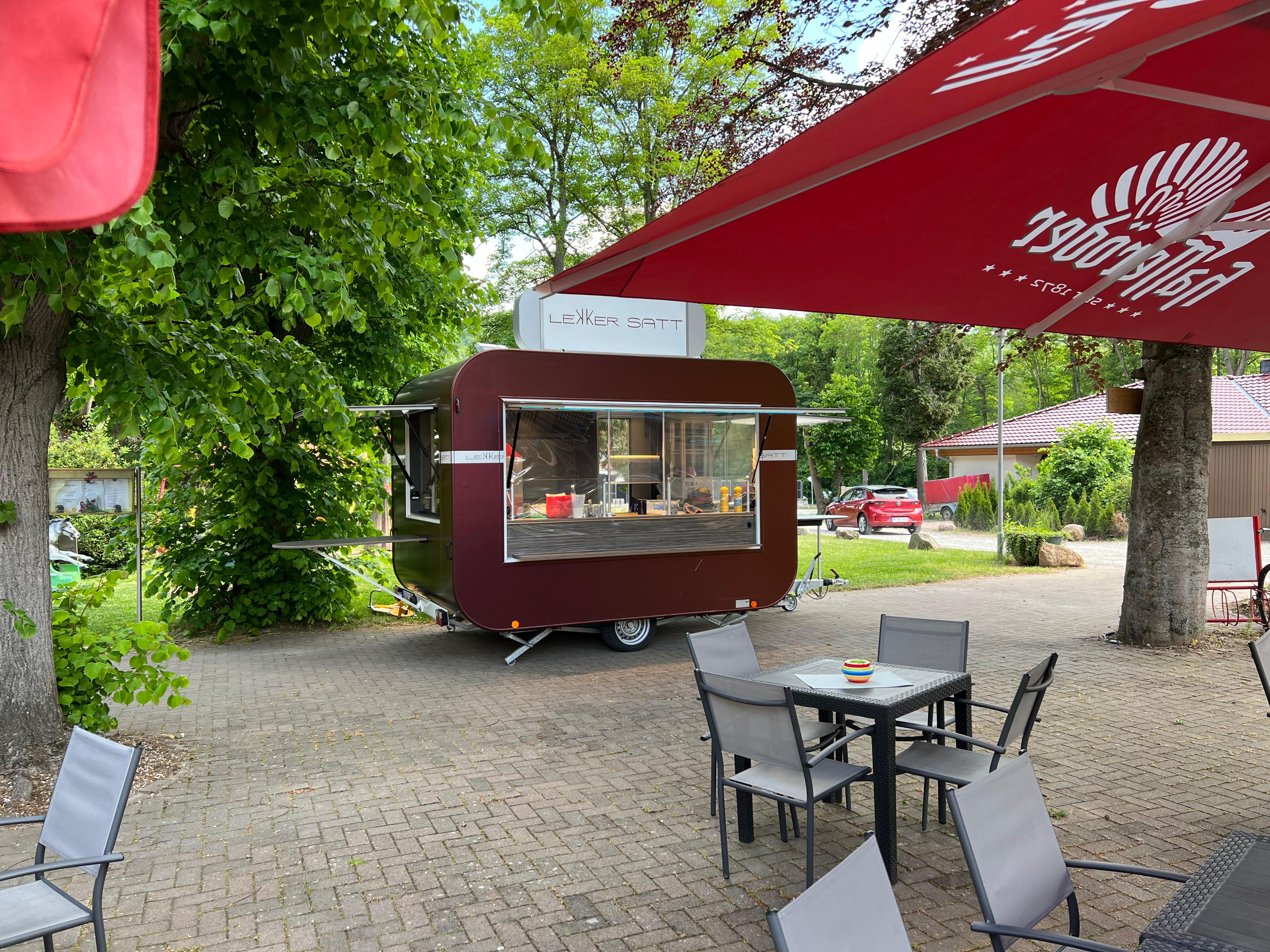 Lekker Satt Food Trailer auf einem Außenbereich mit Sitzplätzen